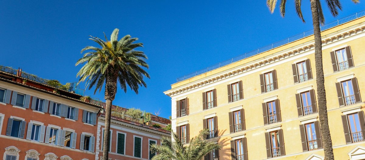 Een palmboom voor gele gebouwen, in een zonnige straat · Italiaanse grammatica C1