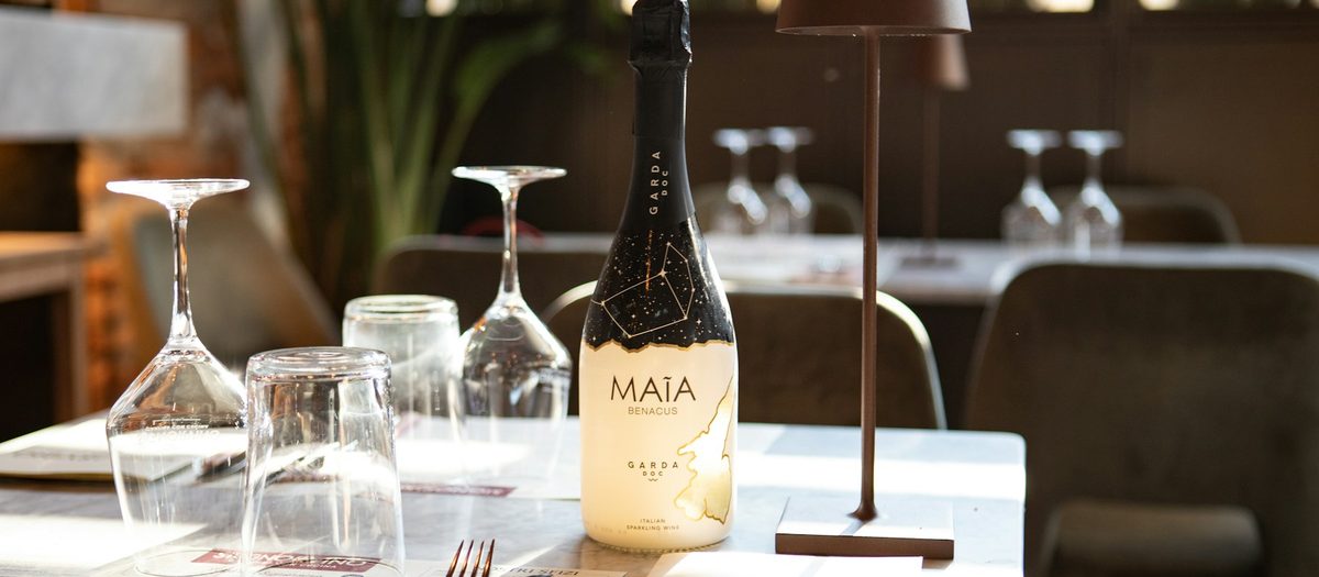 Een fles mousserende wijn en glazen op een gedekte tafel · Italiaanse grammatica A1
