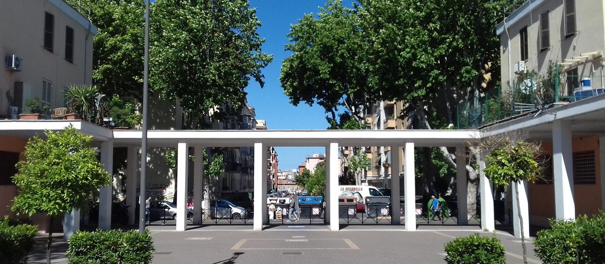 De binnenplaats van een sociale woningbouwblok in Primavalle, Rome, met bomen en zuilengang