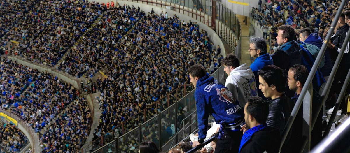 Een volle stadiontribune, de supporters in blauwe shirts · Italiaanse grammatica B1