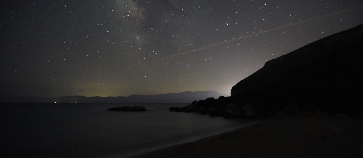 De sterrenhemel boven een baai, ’s nachts