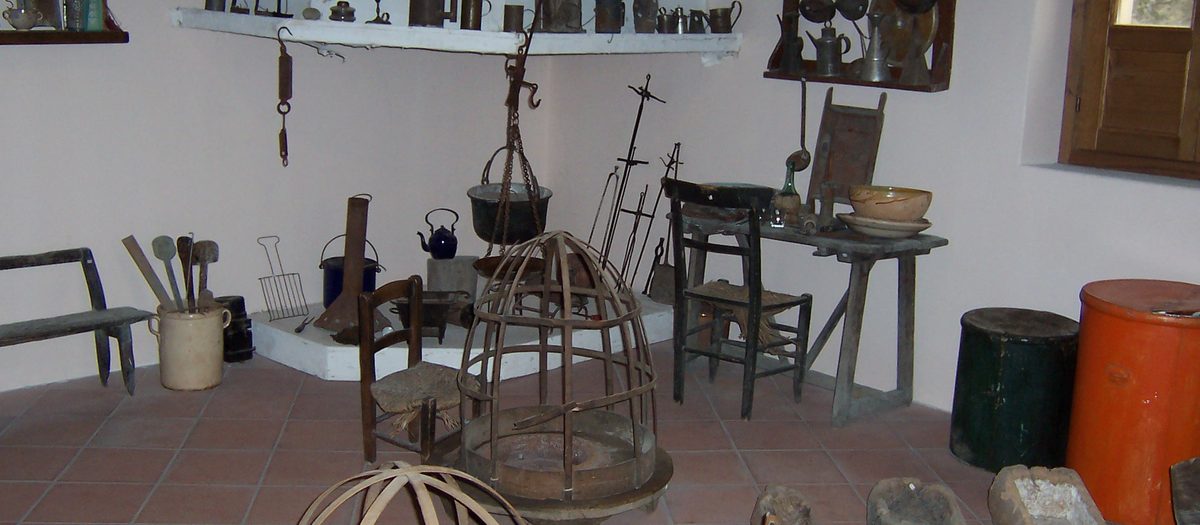 Het interieur van een oude boerderijkeuken, met potten, lampen en stoelen
