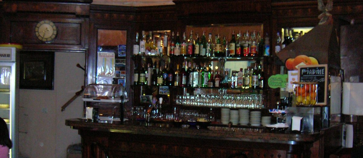 De houten toog van een oude bar, met de flessen op een rij