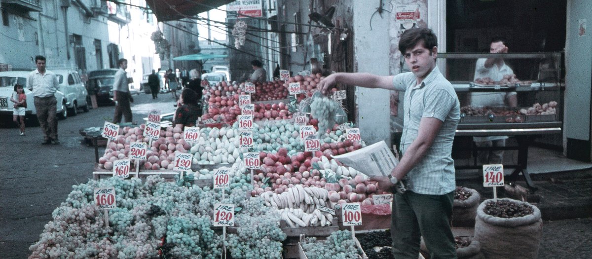 Een Napolitaanse groenteboer in 1970, met kratten en prijskaartjes in lire · Italiaanse grammatica A2