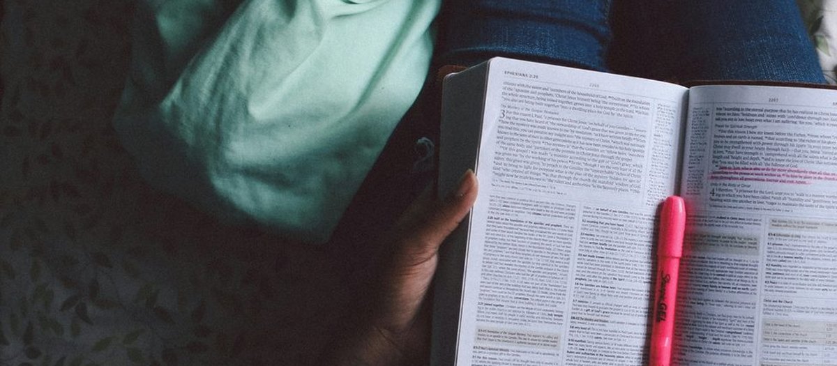 De handen van iemand die een open boek leest, met een markeerstift ernaast · Italiaanse grammatica C2