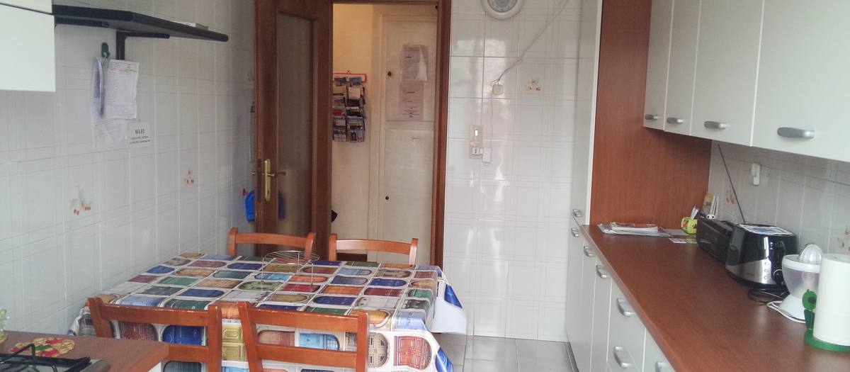 La cucina di una casa vacanze, con il tavolo apparecchiato con una tovaglia colorata