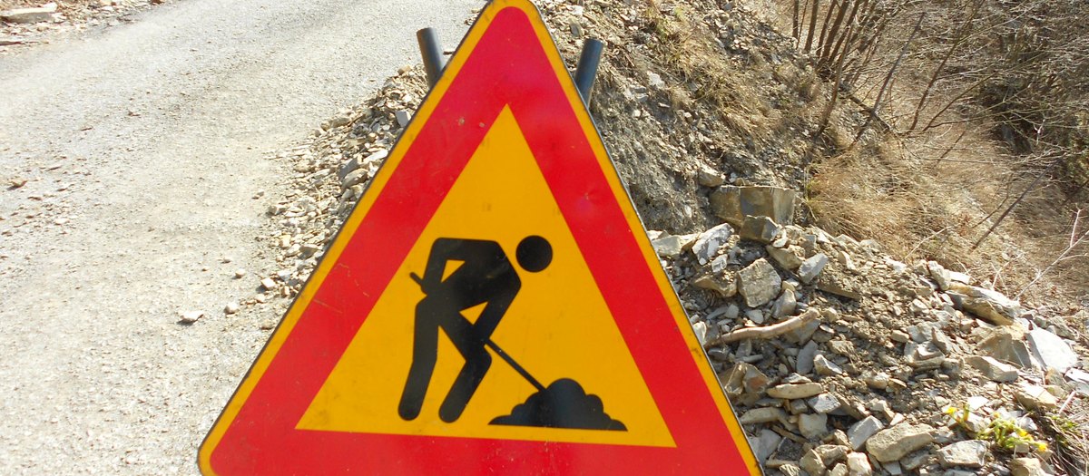 Het driehoekige bord voor wegwerkzaamheden, op een bergweg