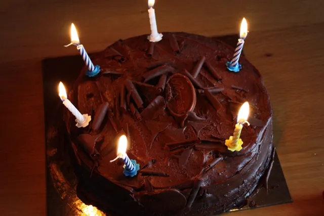 Una torta al cioccolato con sei candeline accese