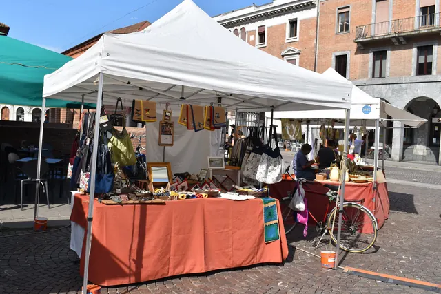 Bancarelle con gazebo bianchi e tovaglie arancioni al mercatino dell'antiquariato e dell'artigianato di piazza Savonarola, a Ferrara