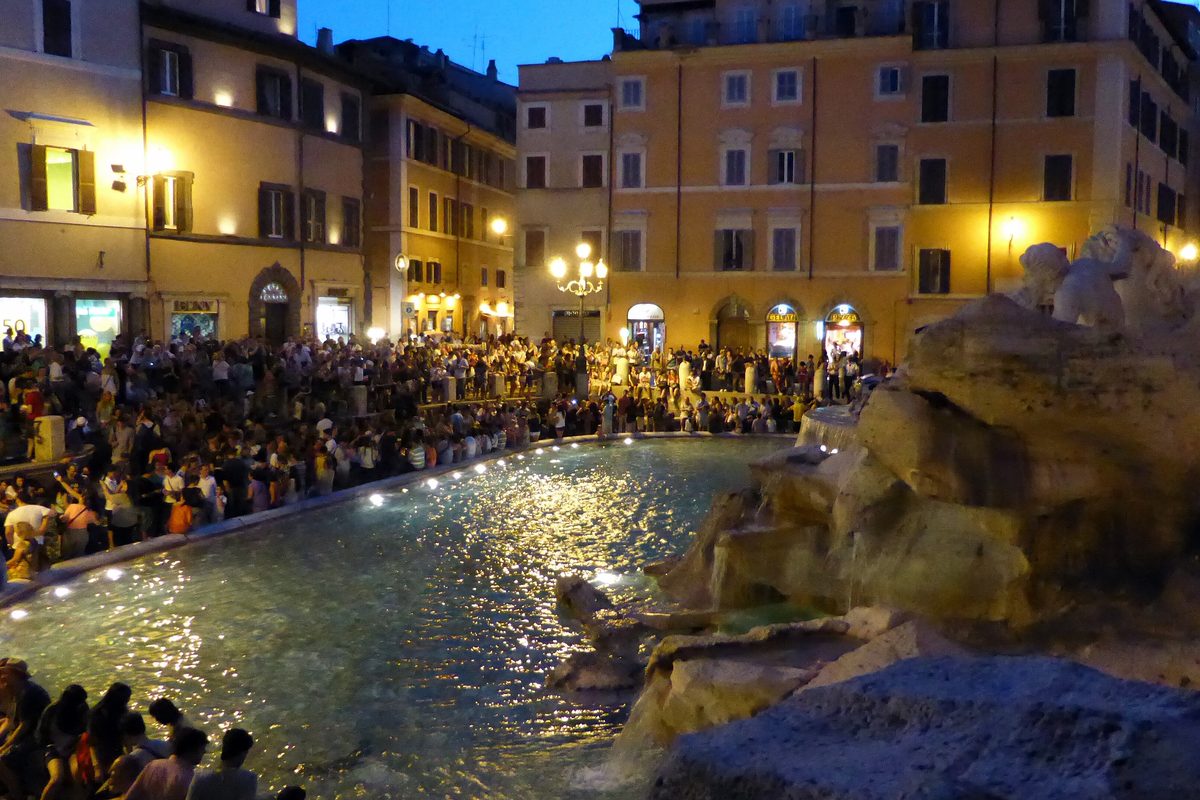 Crowds around the Trevi Fountain in Rome at dusk