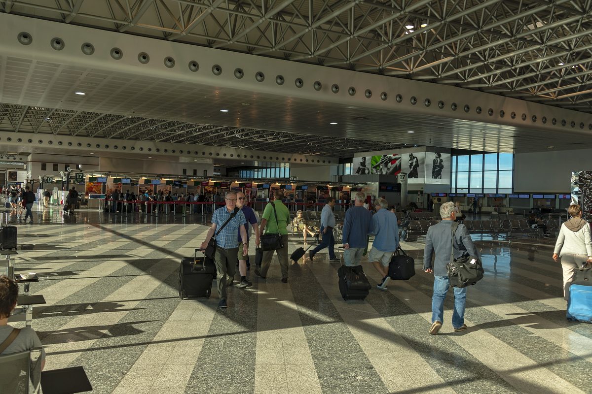 Travellers with suitcases in the check-in hall of Milan Malpensa airport