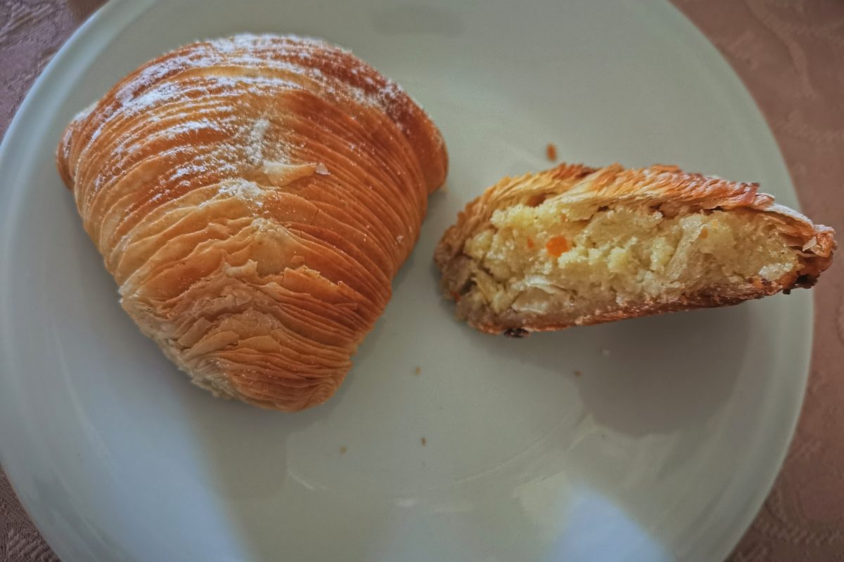 Two sfogliatelle ricce on a plate, one broken open to show the filling