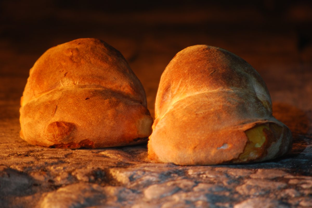 Two golden loaves of Pane di Altamura in a wood-fired oven
