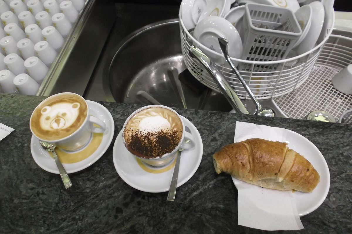 Two cappuccini and a cornetto on the marble counter of a bar in Rome