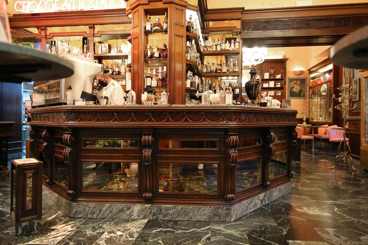 The long wooden counter and shelves of bottles inside Caffè Rivoire in Florence