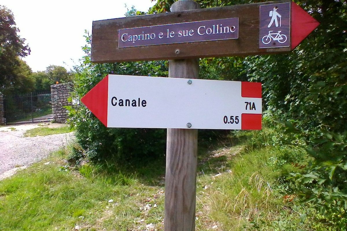 A red and white CAI trail signpost on a hiking path in Italy
