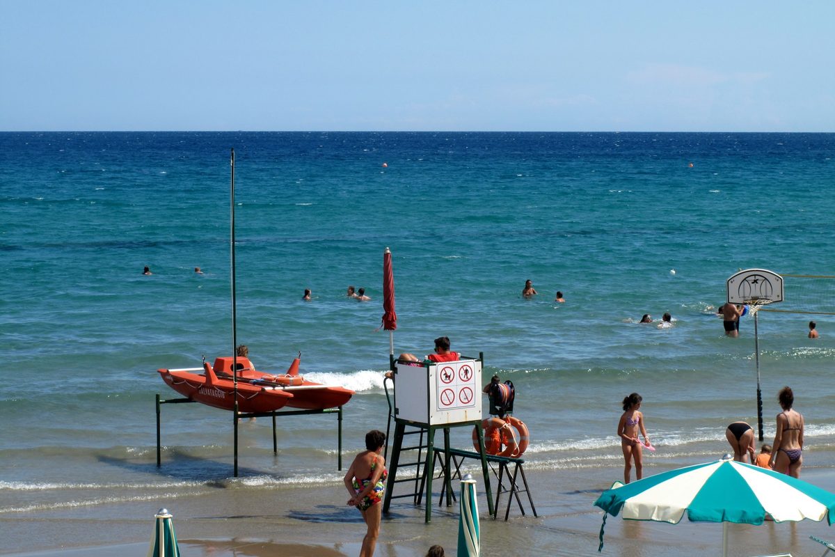 Swimmers by the shore and a lifeguard tower on the beach at Alassio, Liguria