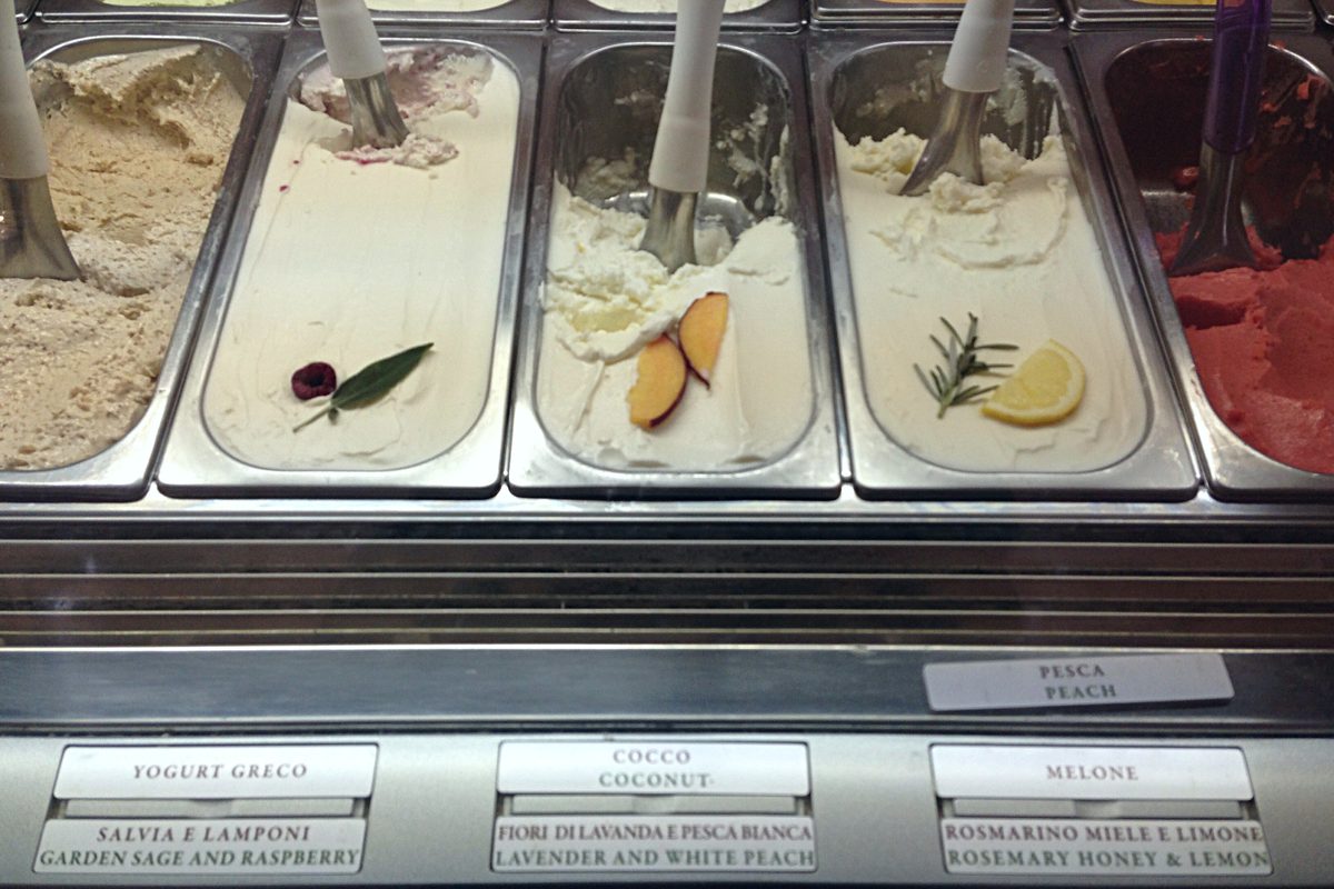 Tubs of artisan gelato with handwritten flavour labels at the Gelateria del Teatro in Rome
