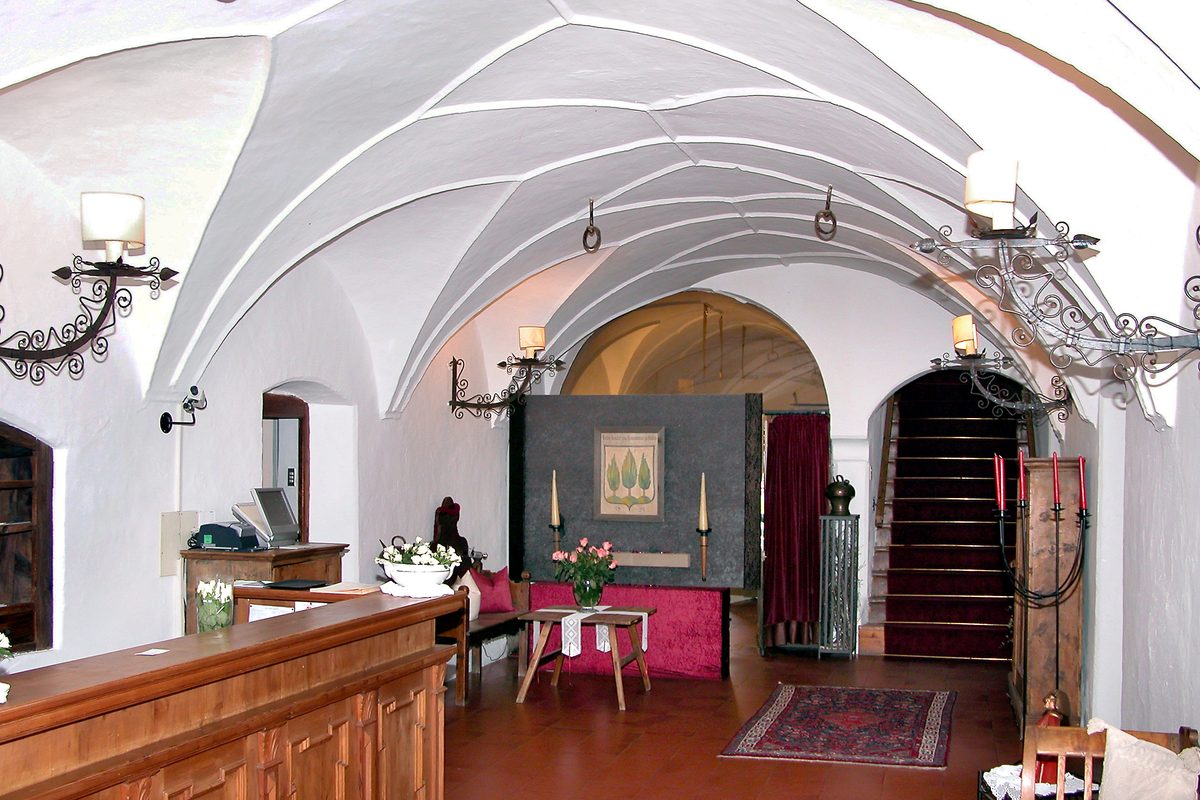 The wooden reception desk of a small hotel under a white vaulted ceiling in South Tyrol