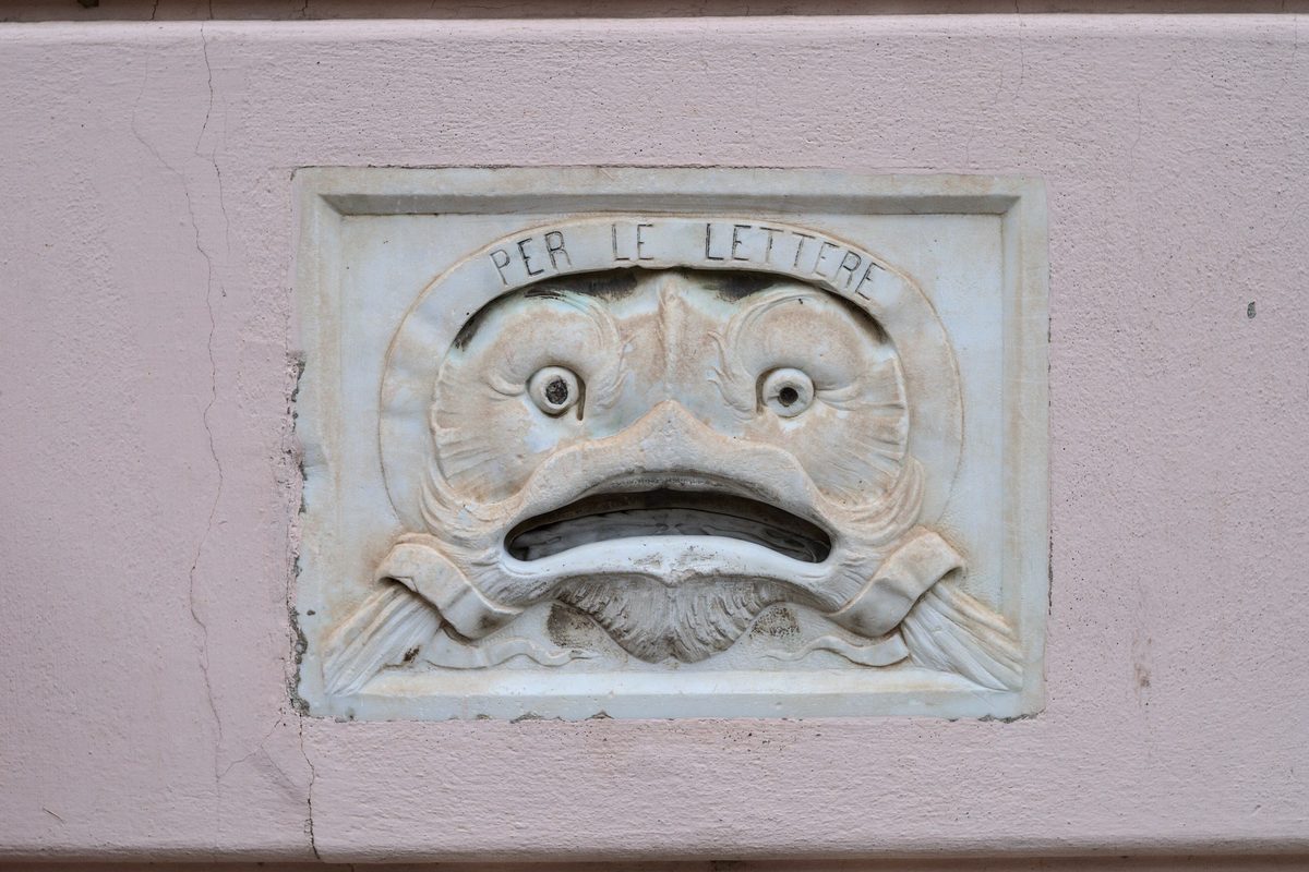 An old carved stone letterbox in the wall of a building in Chianni