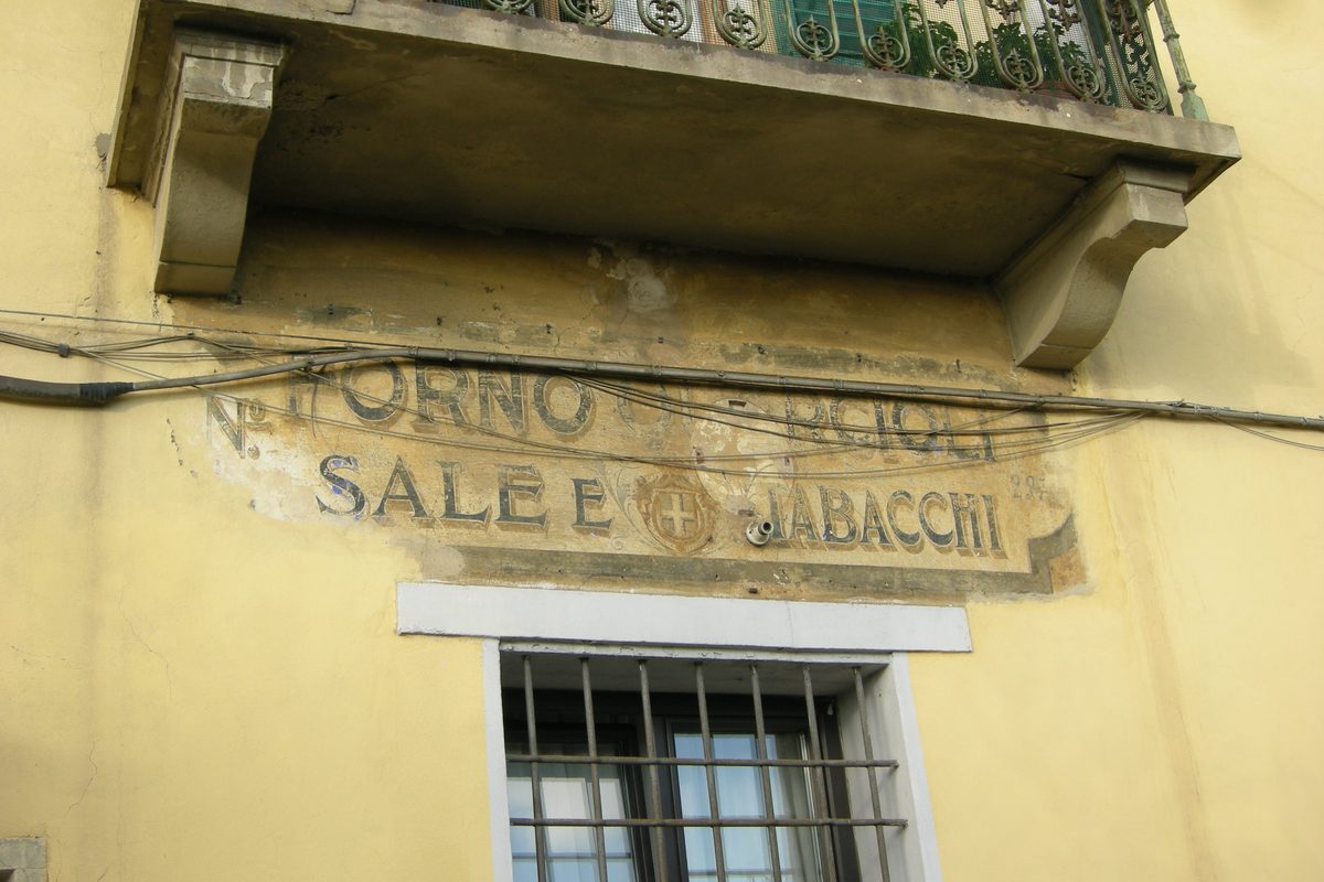 An old painted sign on a yellow wall in Florence: «Forno, sale e tabacchi»