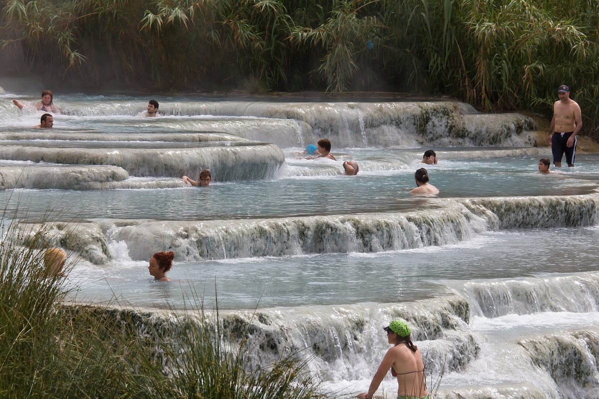 Bathers sitting in the warm limestone terraces of the Cascate del Mulino at Saturnia