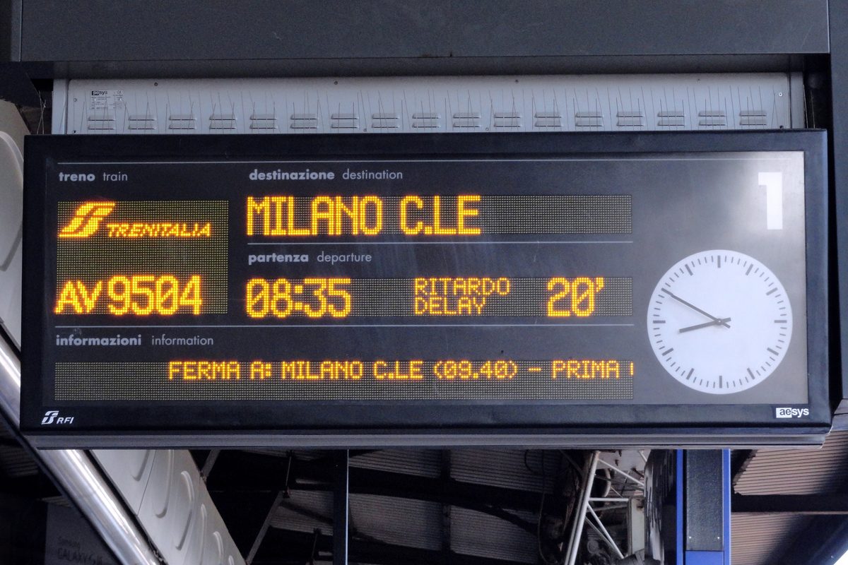 Platform display at Bologna Centrale showing a train to Milano Centrale with a 20 minute delay