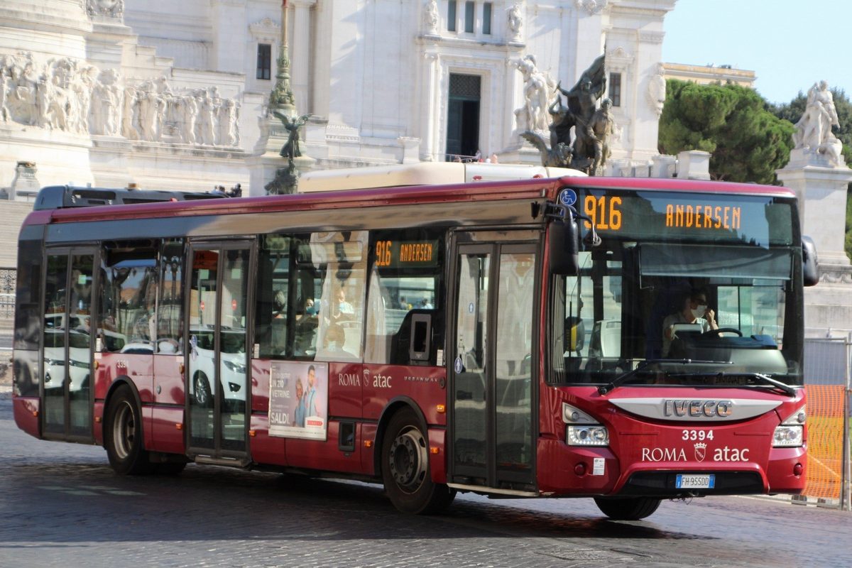 A red ATAC city bus in front of the Vittoriano in Rome