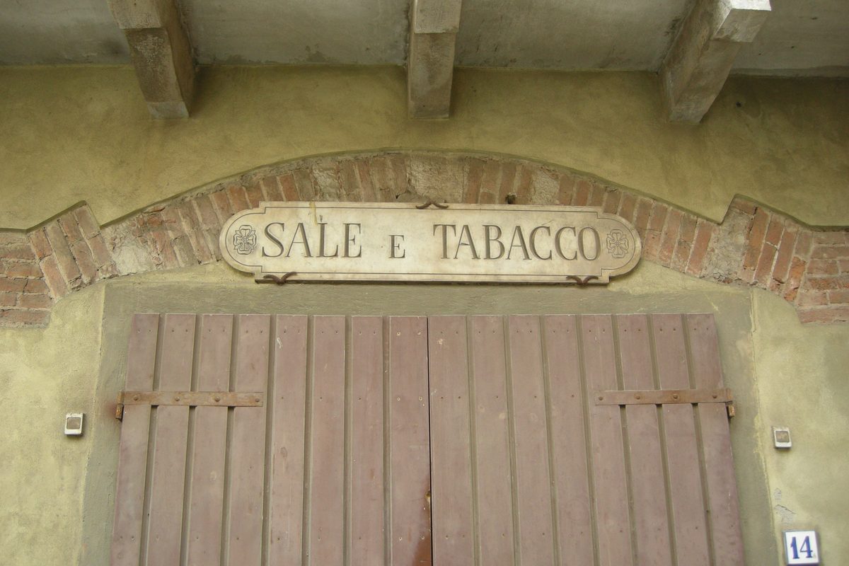 An old marble sign reading «Sale e Tabacco» above a wooden door in Campiglia Marittima