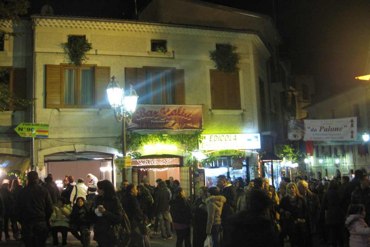 A crowded village street at night during an October chestnut festival