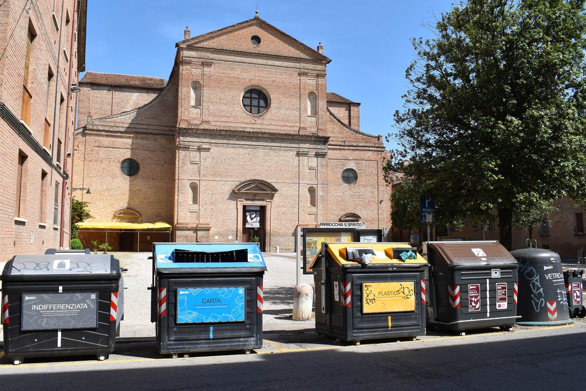 Coloured bins for separated waste in a square in front of a church
