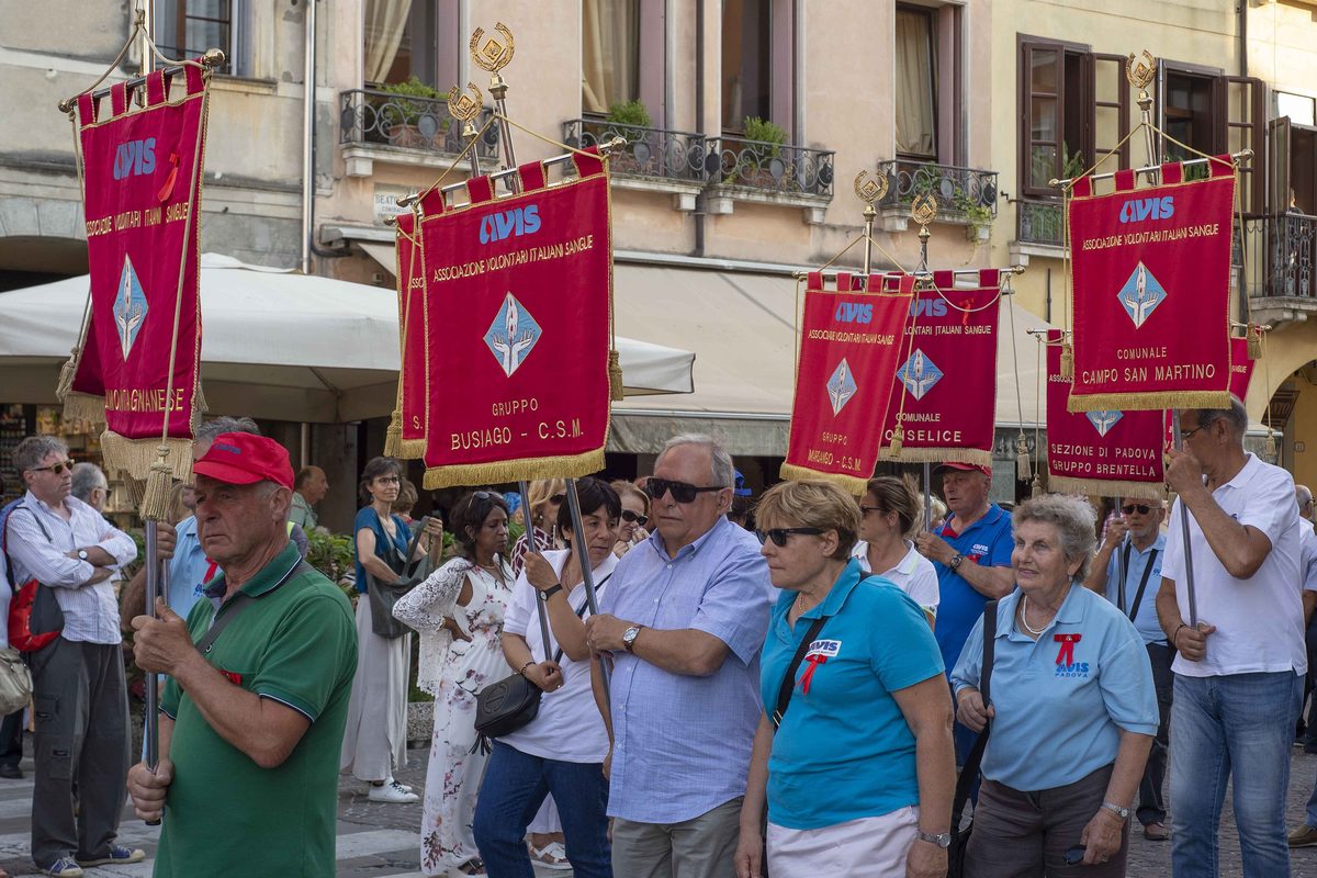 A procession with red banners through the streets of an Italian town