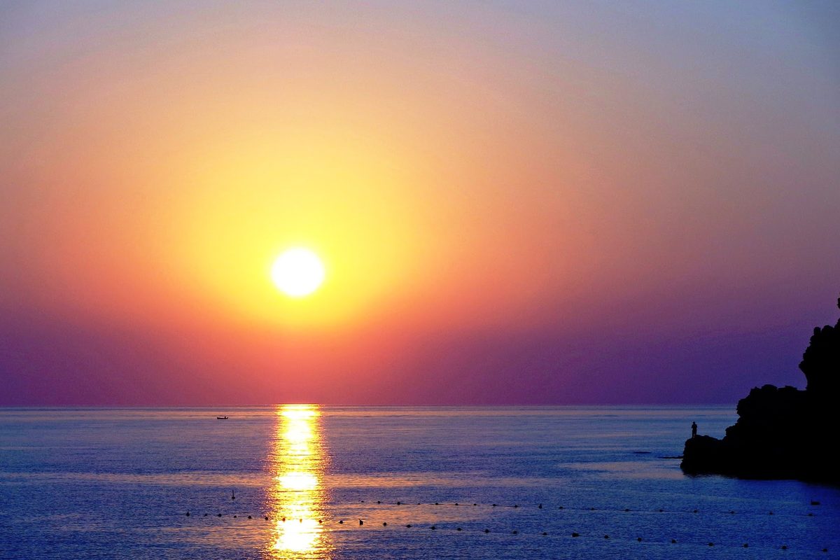 Sunset over the sea at the Baia del Tono near Milazzo, Sicily, at Ferragosto