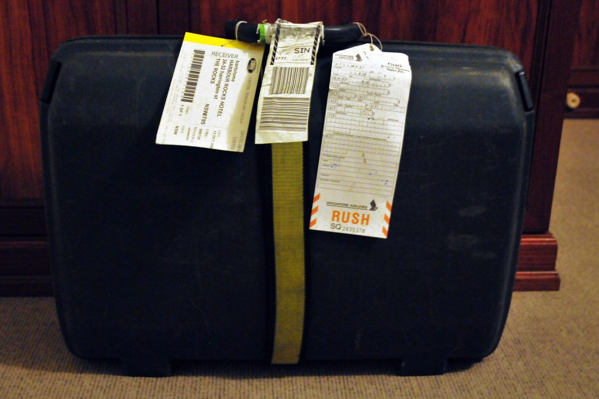 A dark suitcase covered in airline tags and a «Rush» label after being delivered late