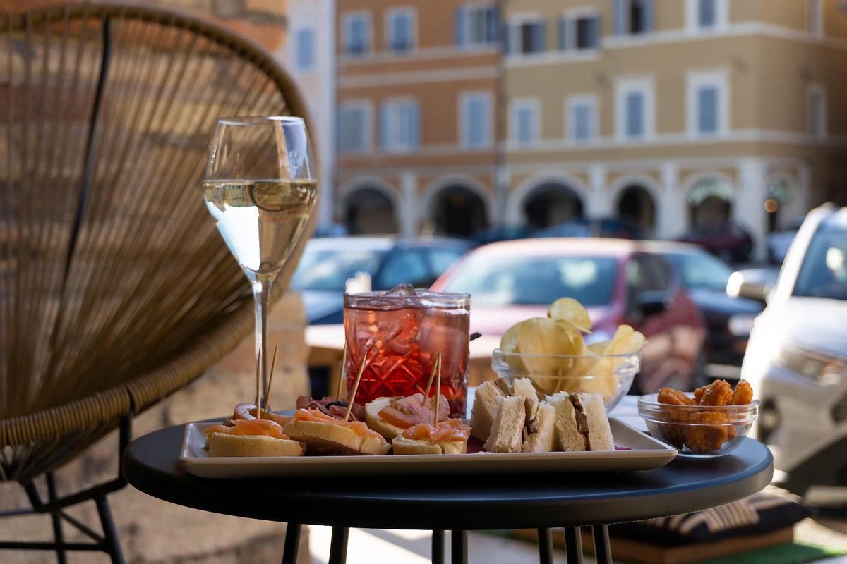 Wine, a spritz and snacks on a table outside a bar in an Italian piazza
