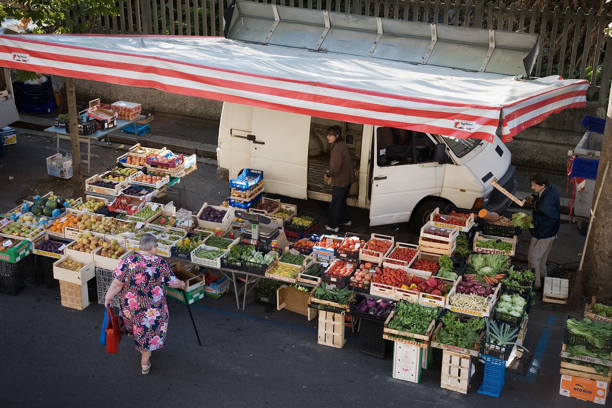 A market stall with fruit and vegetables under a striped awning in Florence