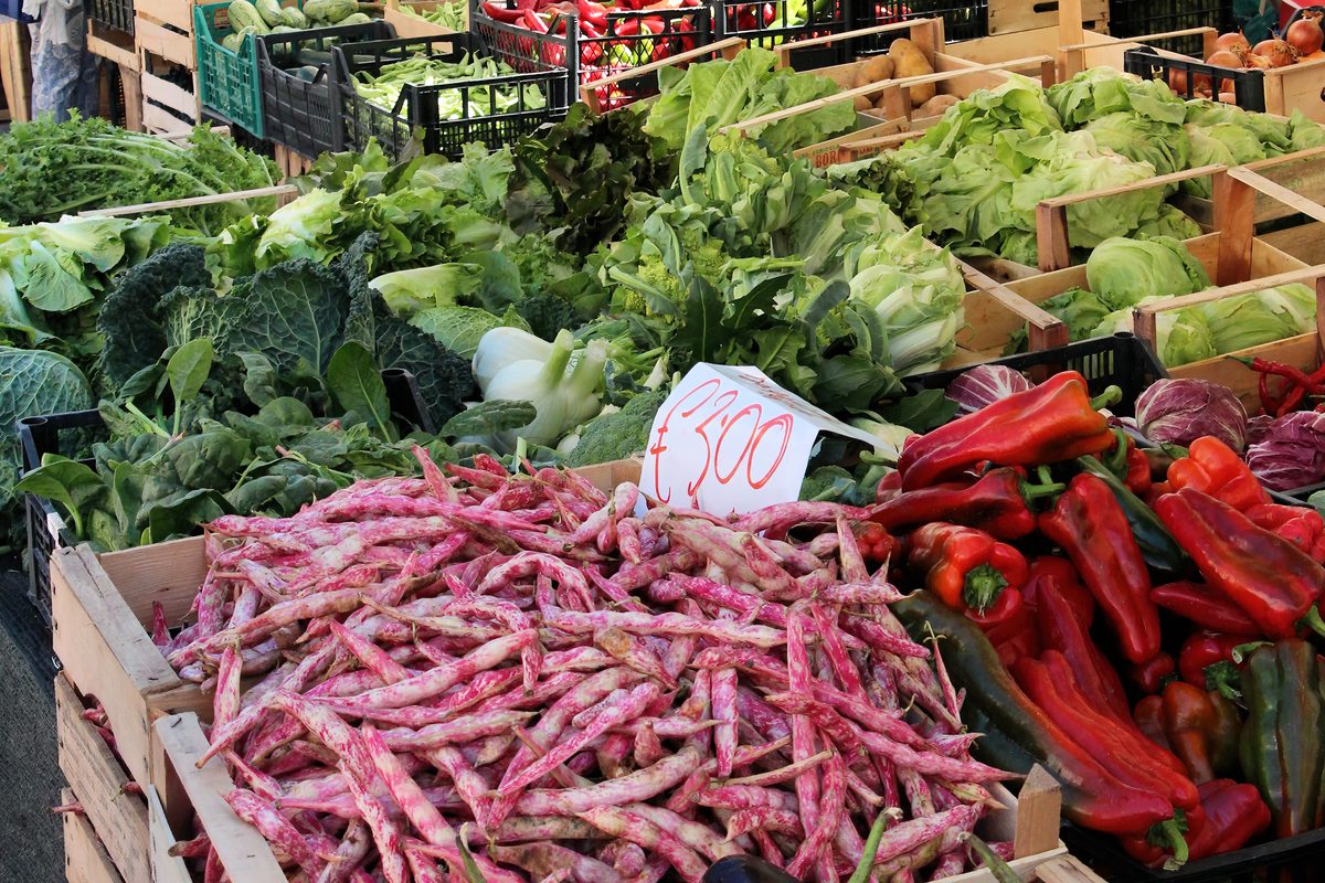 Borlotti beans, red peppers and greens with a price card on a market stall in Sulmona