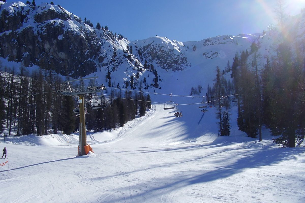 A groomed ski slope with a lift line in the Italian Alps