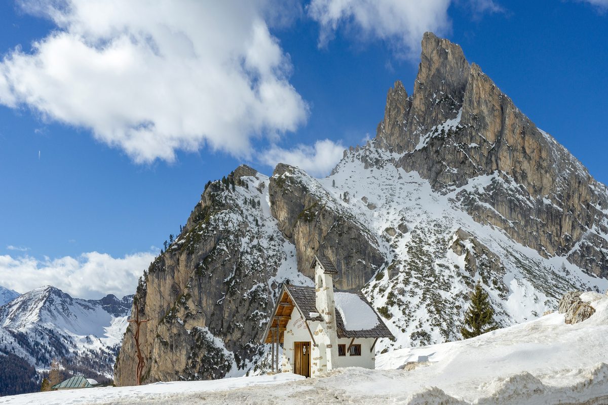 A small chapel in the snow at the Falzarego Pass, with the Sass de Stria peak behind