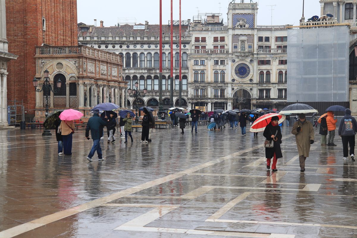 People with umbrellas crossing St Mark's Square in Venice on a rainy day