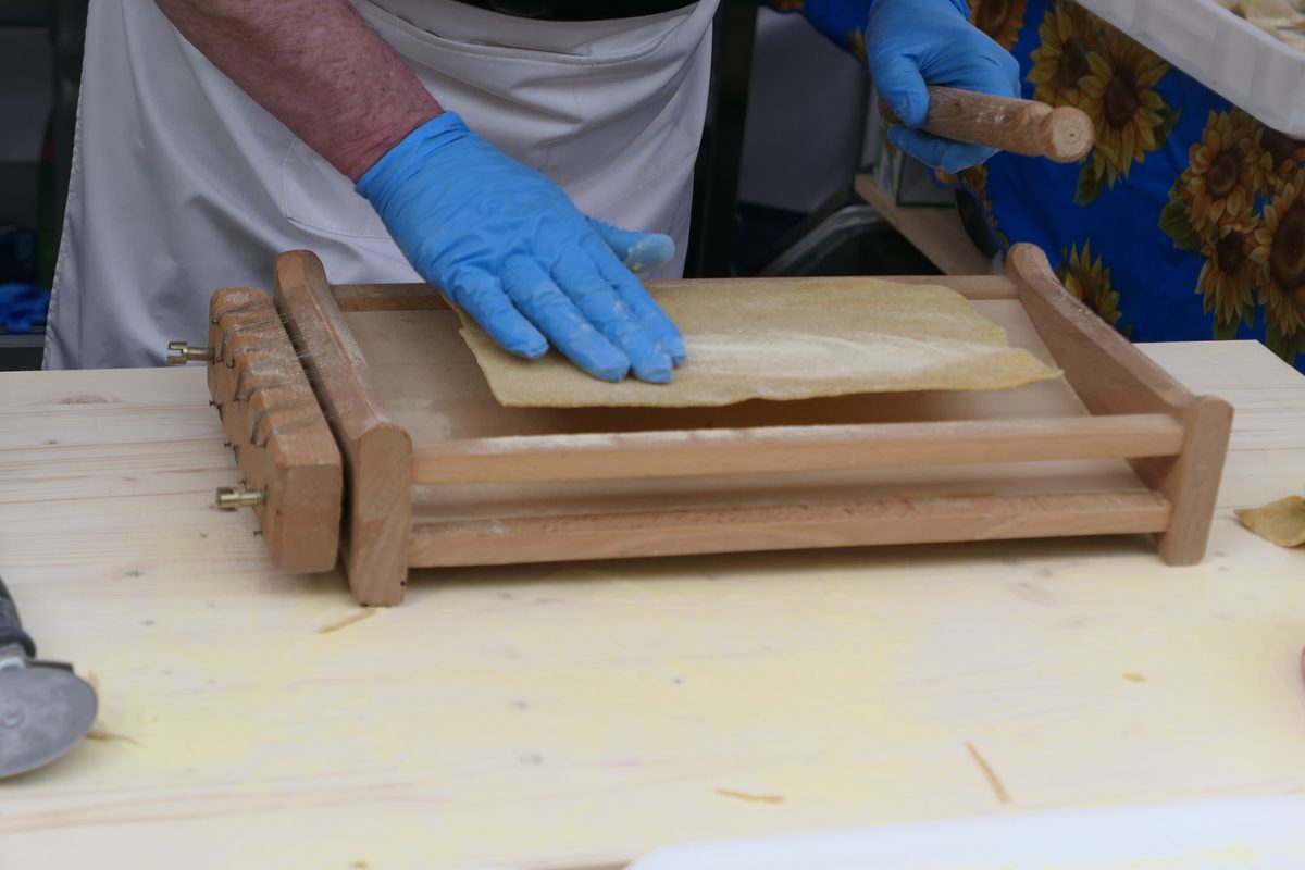 Fresh pasta pressed through the wires of a wooden chitarra frame at a market stall