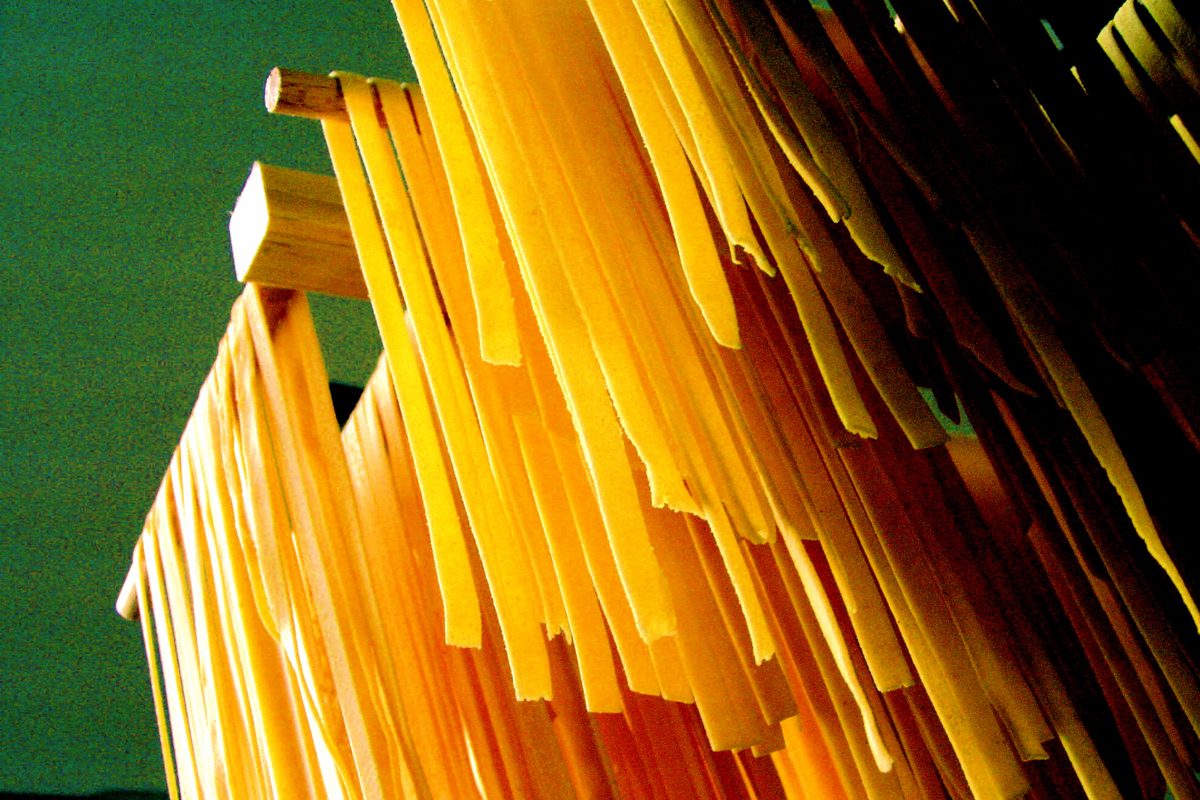 Fresh tagliatelle hanging to dry from wooden bars