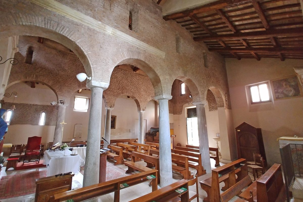 The left aisle of the small church of San Lazzaro in Rome, with wooden pews and columns